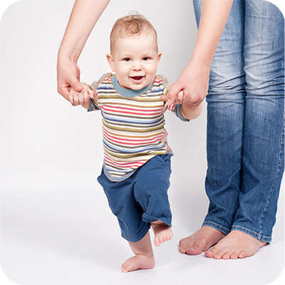 bebé a dar os primeiros passos agarrado às mãos de um adulto