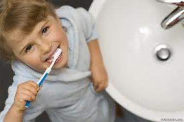 menino com a escova na boca olha para cima