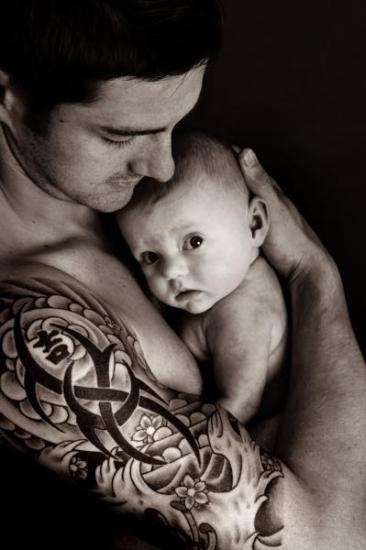 senhor com tatuagem no braço abraça bebe