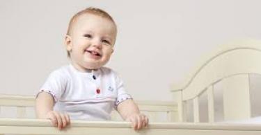 bebe sorrindo de pé no berço