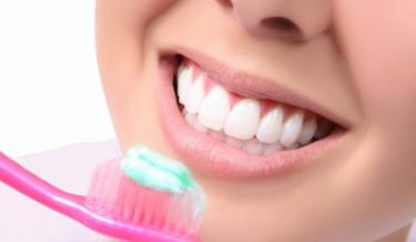 escova de dentes cor de rosa com pasta em frente a boca