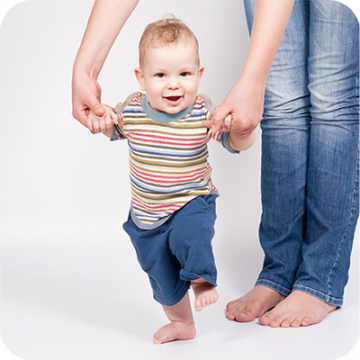 bebé a dar os primeiros passos agarrado às mãos de um adulto